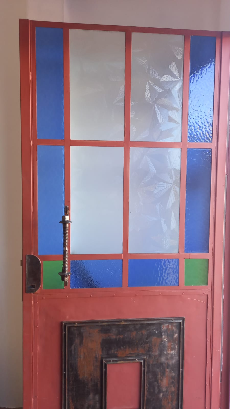 Puerta restaurada en rojo con vidrios azules y verdes