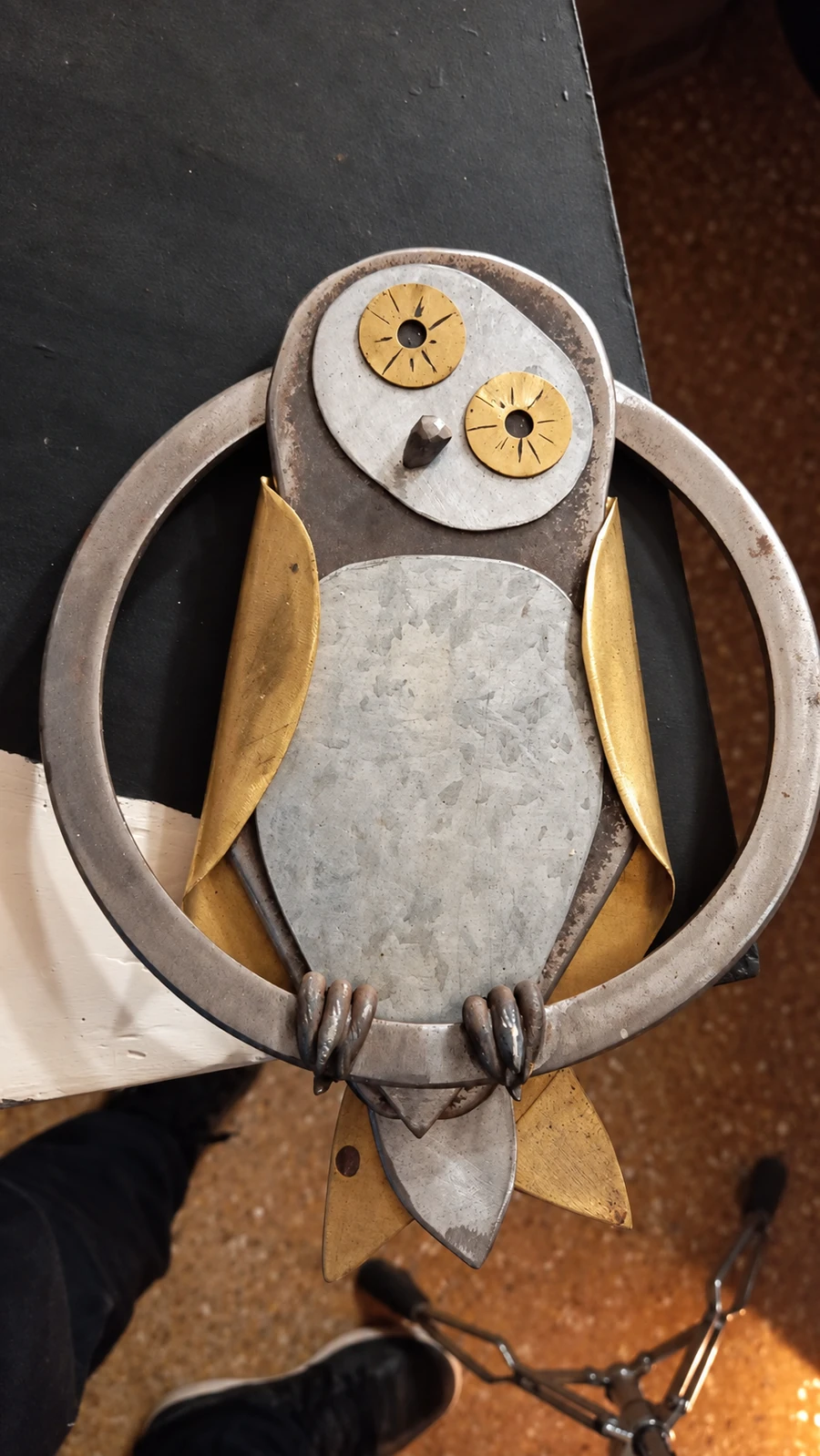 La lechuza de cerca, con las alas doradas y la textura del metal a la vista.