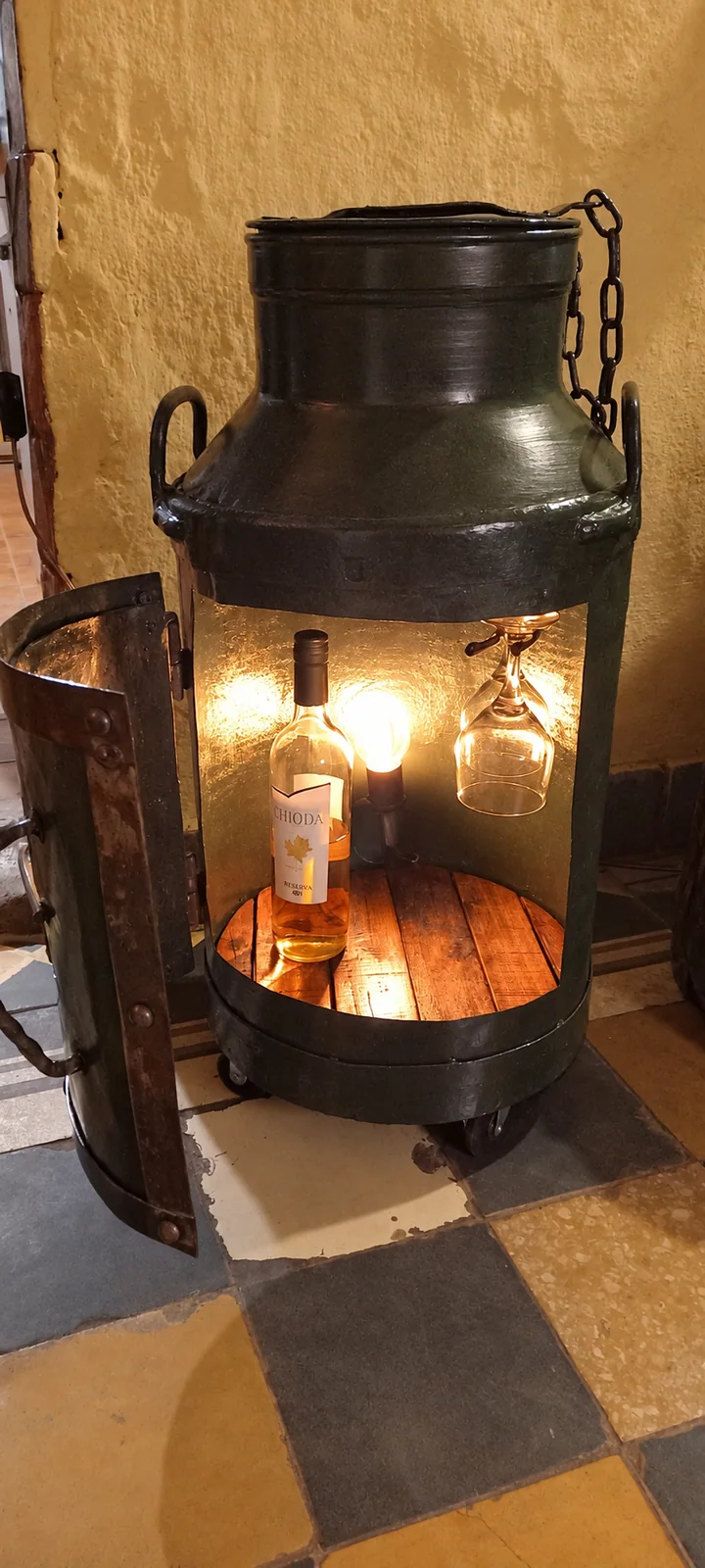 La bodega abierta, con el interior iluminado y las copas a la vista.