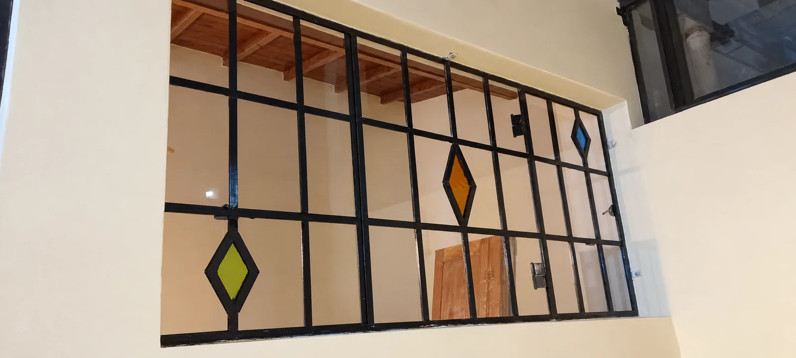 Los rombos de vidrio de colores se integran al dibujo de la reja.